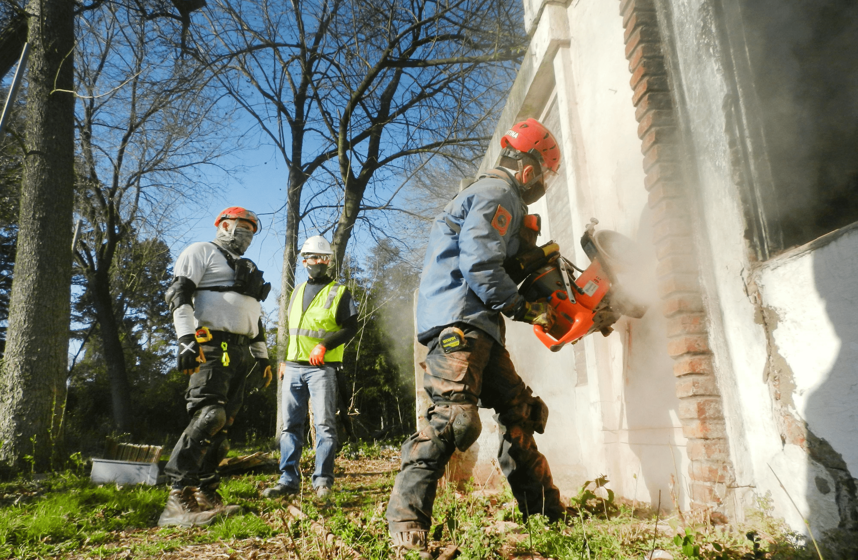 Demolition workers using a tool to tear down an exterior wall