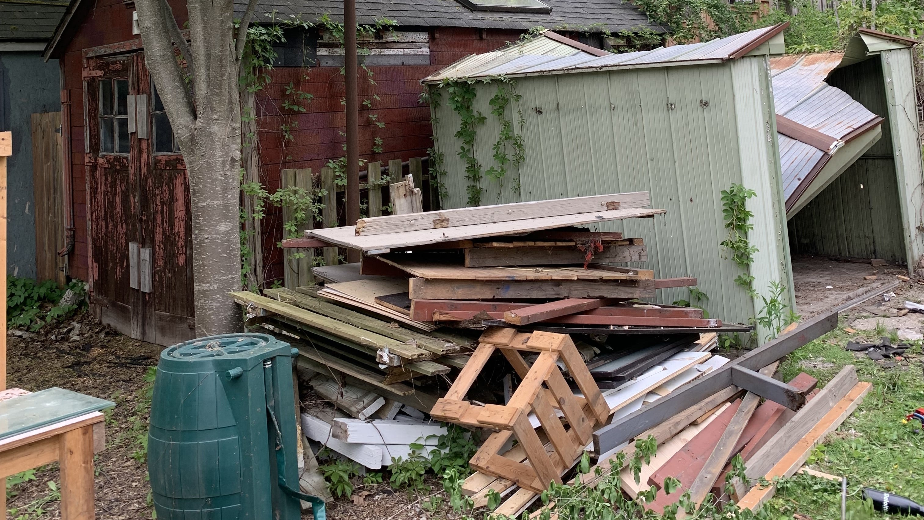 Pile of old broken down fence next to a collapsed metal shed 